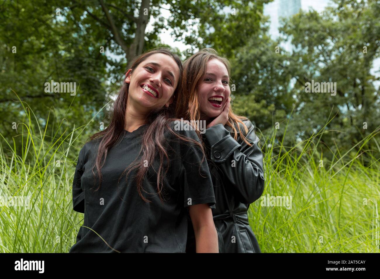 Porträt zweier glücklicher junger Frauen mit unterschiedlichen rassischen Hintergründen. Einer lehnt sich an den anderen an. Mittlere Aufnahme. Stockfoto