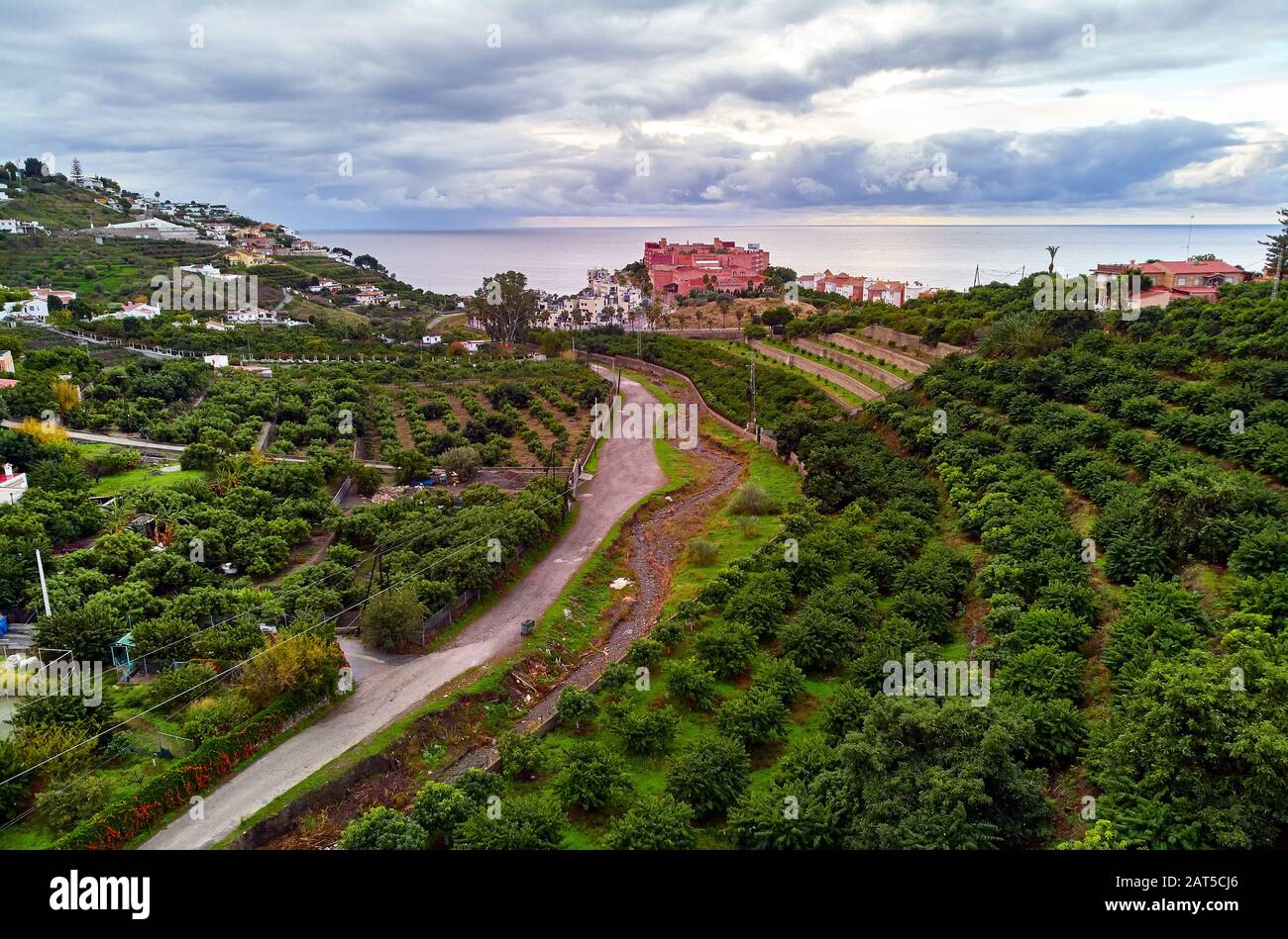Luftbild der Stadt am Hang am Meer, Drone Almuñécar. Malerische Hügel, Täler, landwirtschaftliche Landschaft. Moody bewölkt Himmel über Meer Spanien Stockfoto