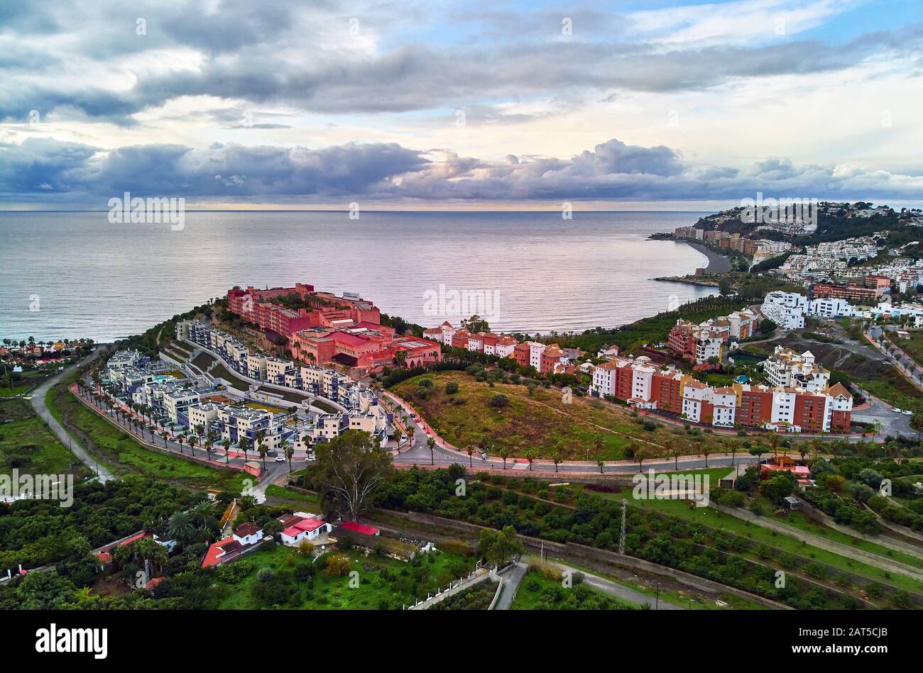 Luftbild der Stadt am Hang am Meer, Drone Almuñécar. Malerische Hügel, Täler, landwirtschaftliche Landschaft. Moody bewölkt Himmel über Meer Spanien Stockfoto