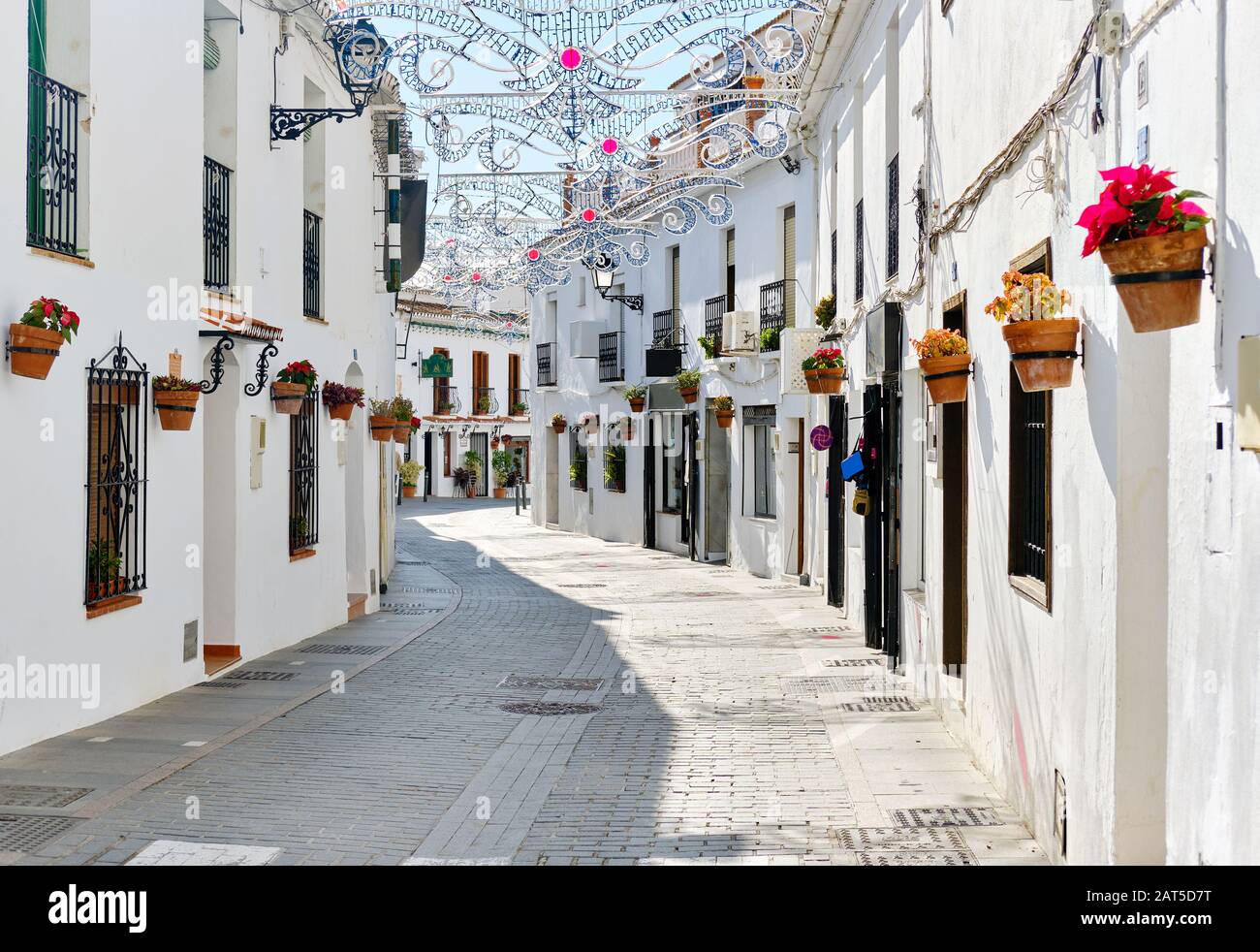Mijas weiße Straße, kleines berühmtes Dorf in Spanien. Charmante, leere Gassen mit Neujahrsdekorationen, an den Wänden hängen Blumentöpfe Stockfoto