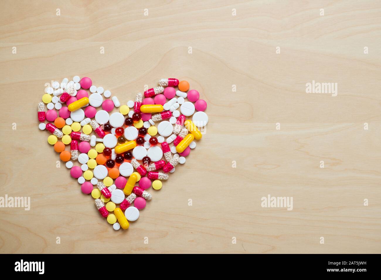 Pillen auf dem Tisch zeigen eine Herzform. Konzept der Herzerkrankung Stockfoto