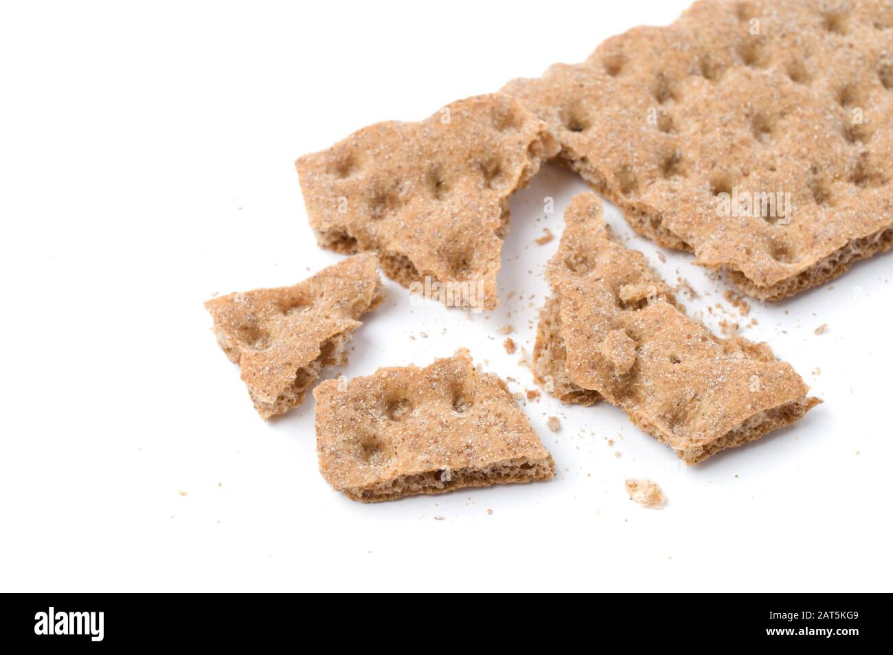 Knackiges knuspriges Brot mit Krümel auf weißem Hintergrund. Selektiver Fokus und geringe Schärfentiefe. Stockfoto