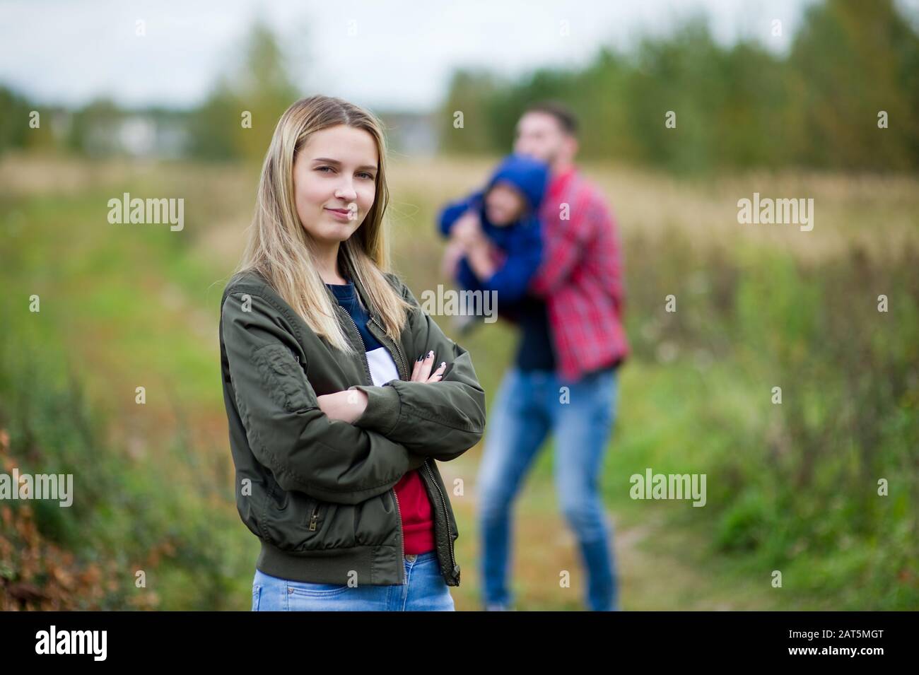 Mutter lächelt, und im Hintergrund spielt ihr Mann mit dem kleinen Sohn. Selektiver Fokus Stockfoto