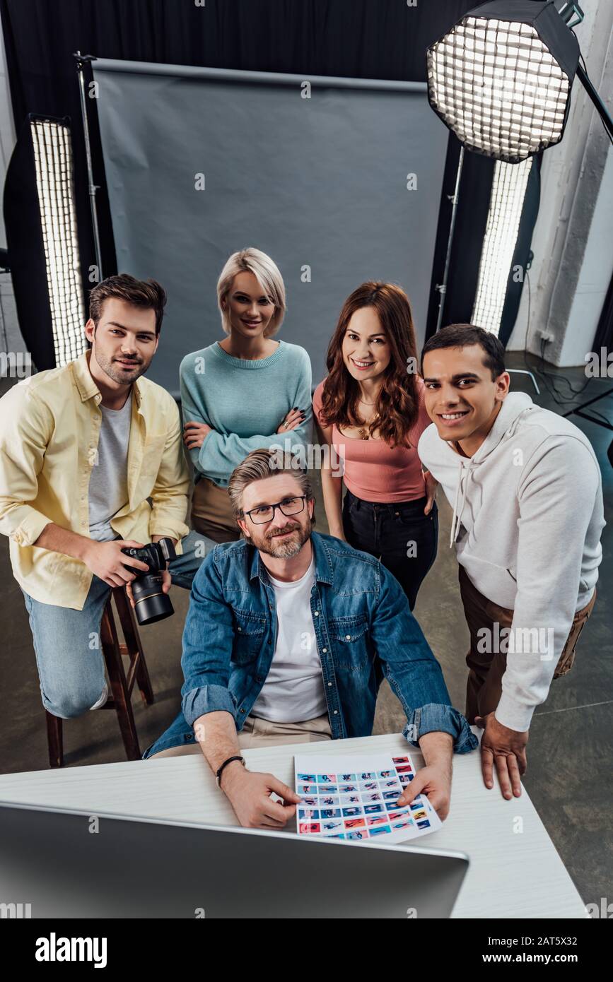 Overhead-Ansicht des fröhlichen Kreativ-Direktors und der Assistenten, die die Kamera im Fotostudio betrachten Stockfoto