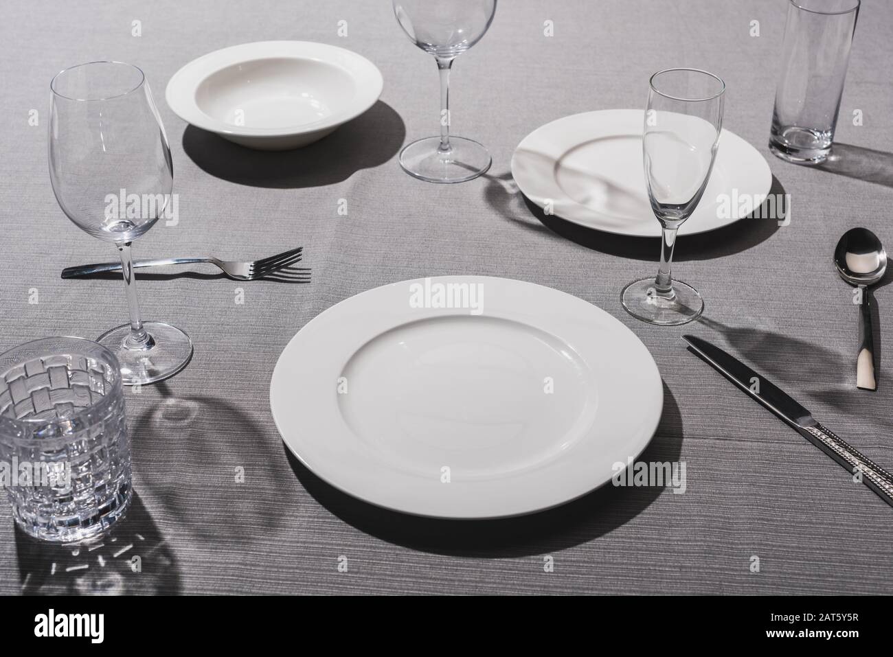 Leeres Geschirr mit Gläsern auf grauem Tuch Stockfoto