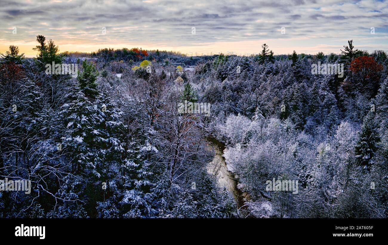 Schöne schneebedeckte Landschaft eines fließenden Flusses in einem Stadtpark mit verschneiten Bäumen, Stockfoto