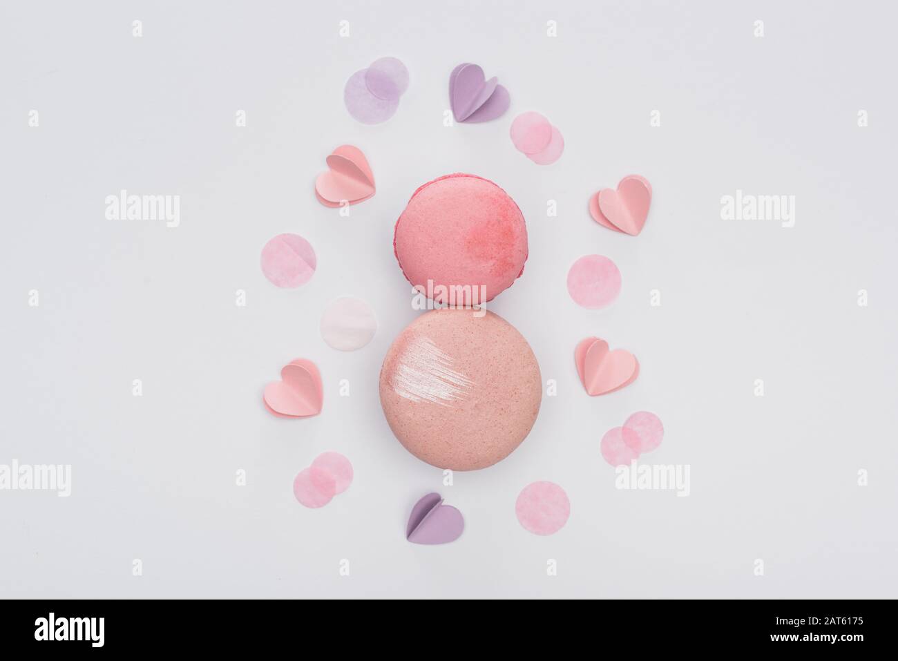 Draufsicht auf rosafarbene Makronen und violette Herzen isoliert auf Weiß Stockfoto