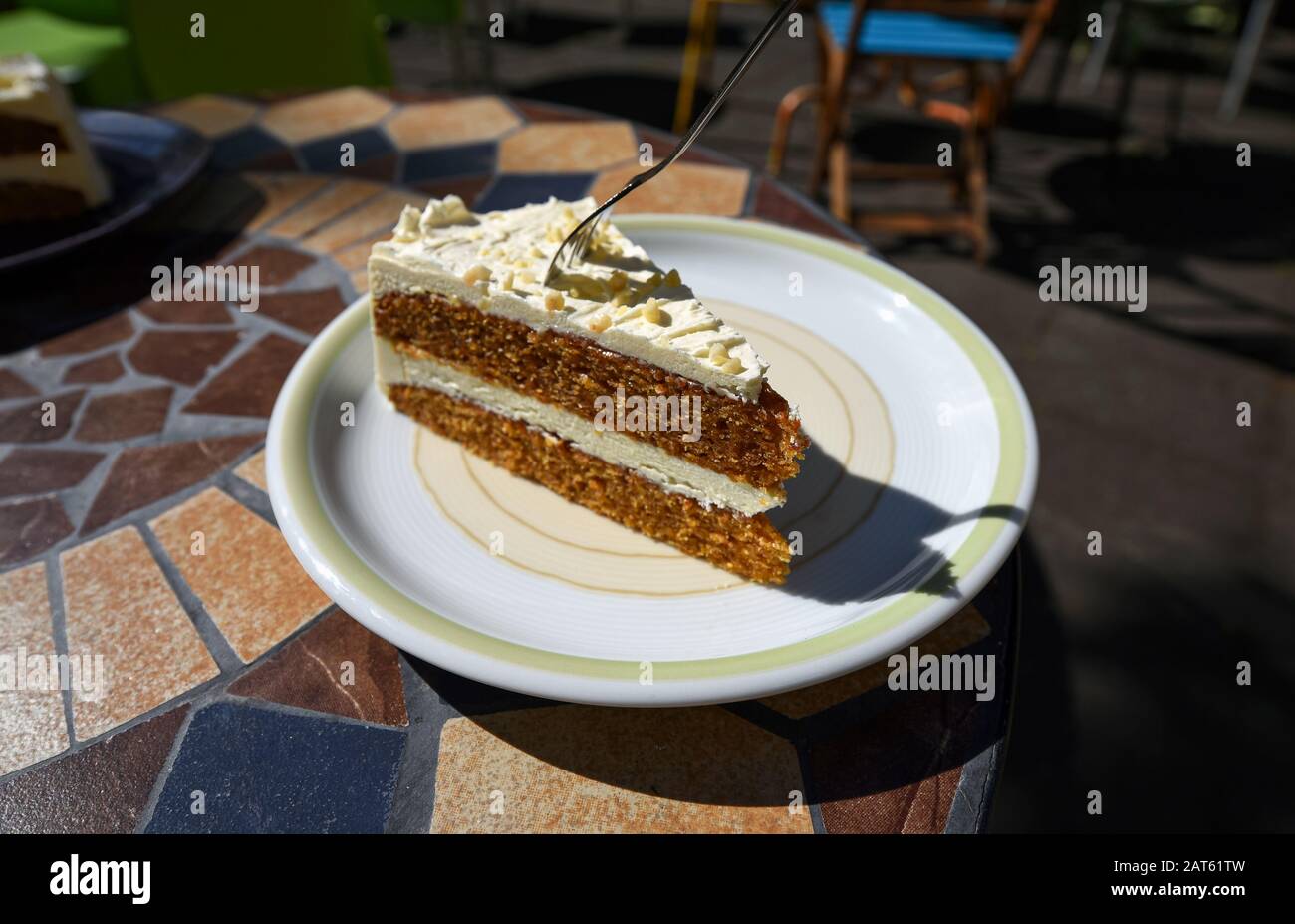 Leckerer Karottkuchen mit einer Gabel, die an einem sonnigen Tag auf einem Teller in einem Café serviert wird. Stockfoto