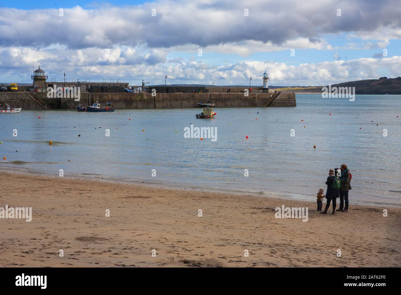 Eine junge Familie am Strand am Hafen von St. Ives bei halber Flut von der Wharf Road, St Ives, Cornwall, England, Großbritannien. MODELL VERÖFFENTLICHT Stockfoto