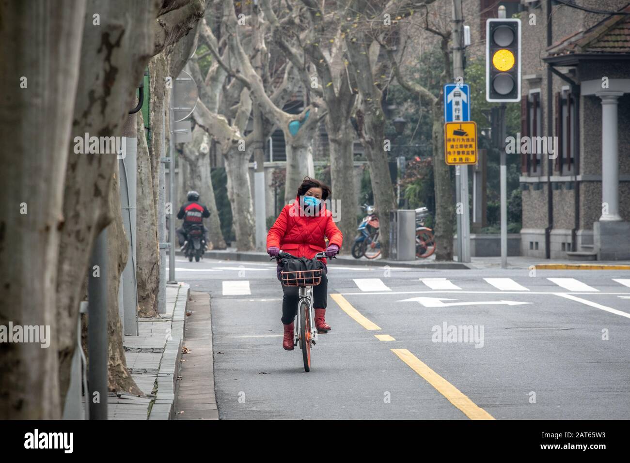 Shanghai, China, 27. Januar 2020, EINE Frau, die mit ihrem Fahrrad unterwegs ist und eine Maske auf einer fast leeren Straße trägt, um das Coronavirus nicht zu fangen Stockfoto