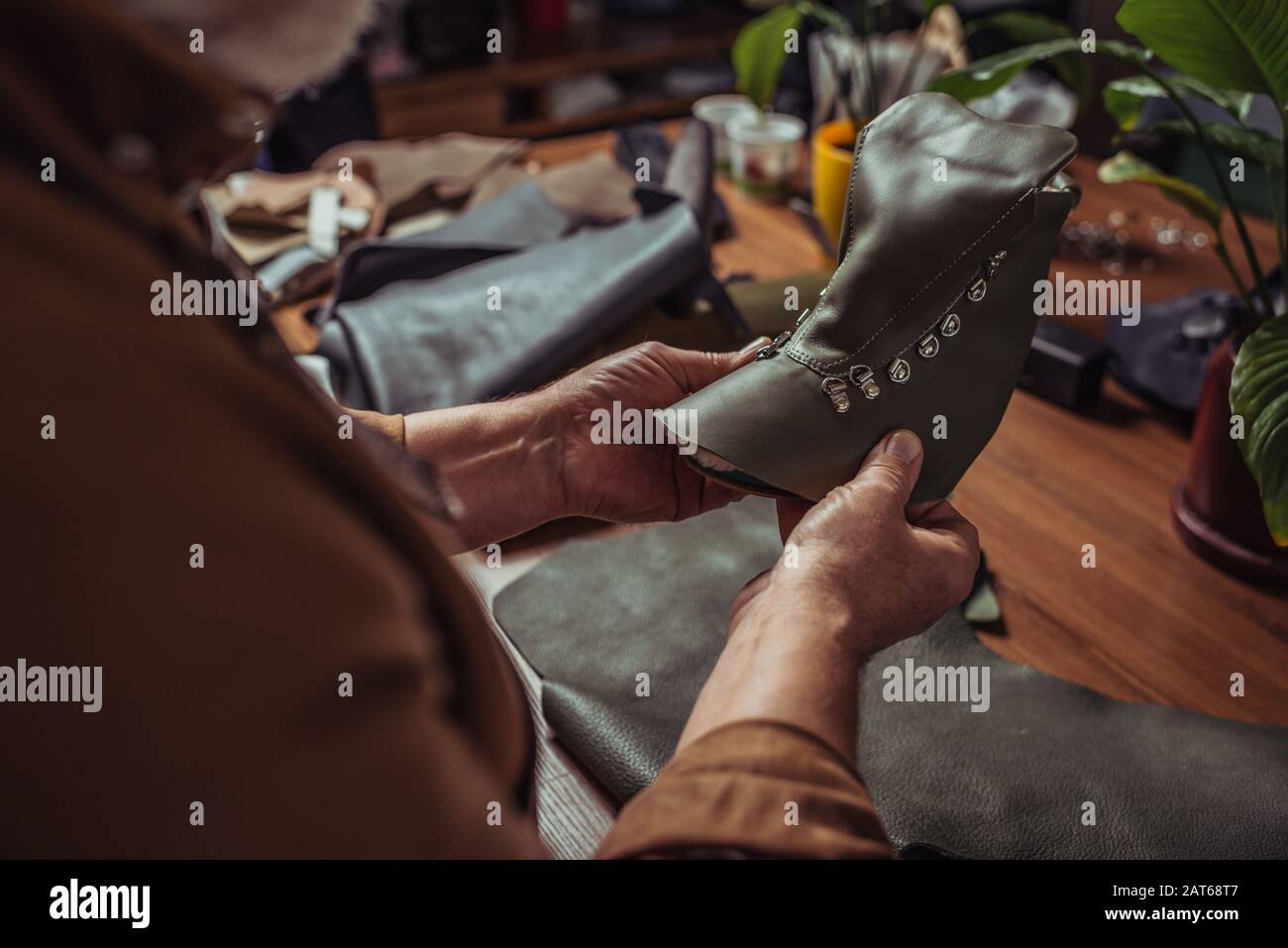 3/4-Ansicht des Schuhmachers mit Lederdetails des unfertigen Schuhs in der Werkstatt Stockfoto
