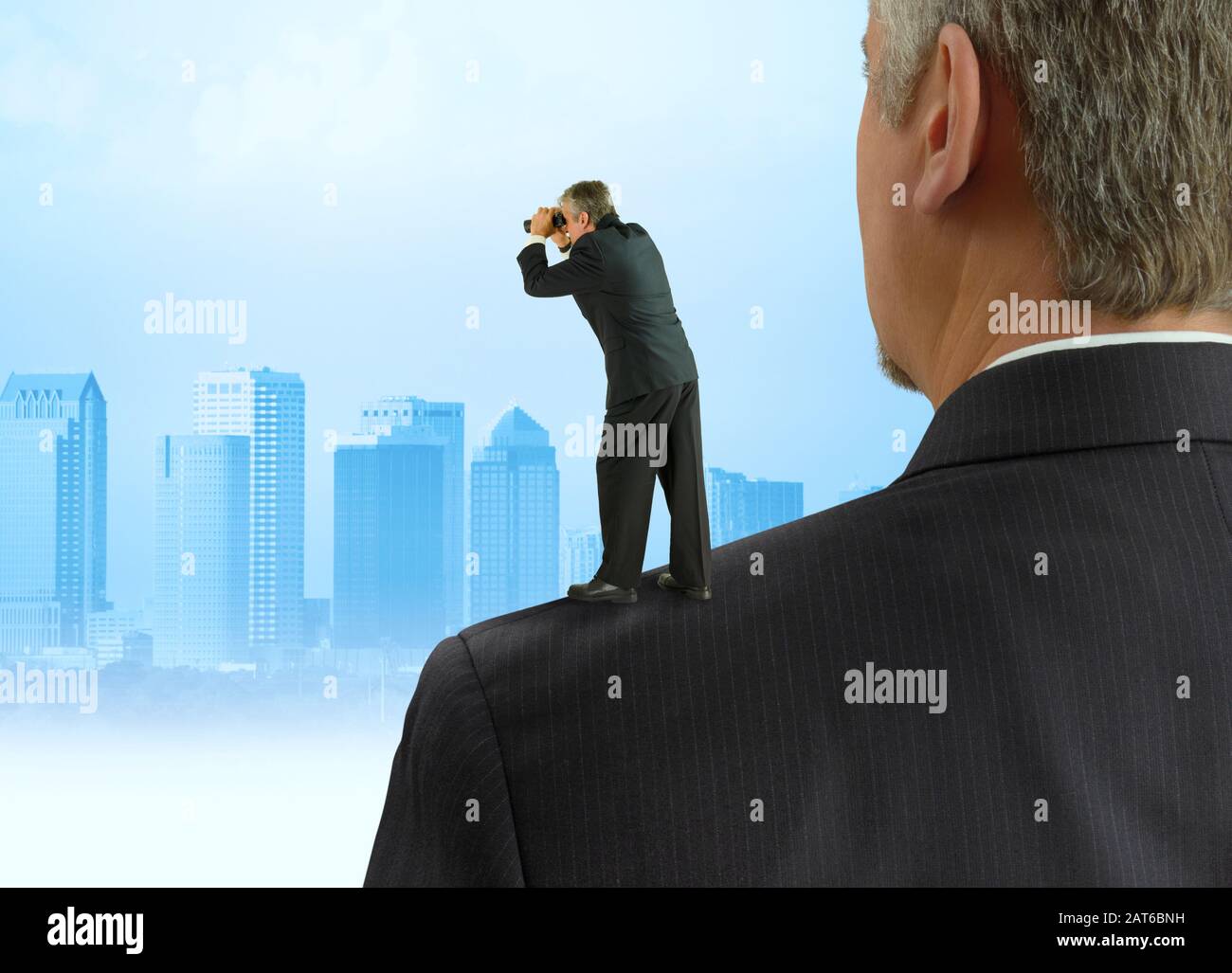 Mann mit Ferngläsern, die auf den Schultern von Giganten stehen, Konzept mit Stadtbild, das von der Arbeit früherer Menschen profitiert Stockfoto