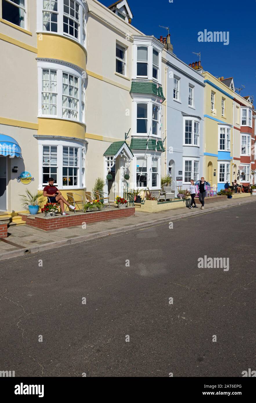 Farbenfrohe Häuser und Hotels aus der viktorianischen Zeit säumen eine Straße am Meer in Weymouth, Dorset, Großbritannien Stockfoto