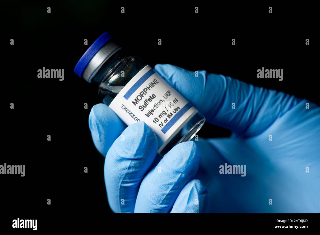 Morphin-Sulfat-Injektionsfläschchen, die von der Handschuhhand des Gesundheitsperformers mit dunklem Hintergrund gehalten werden. Stockfoto
