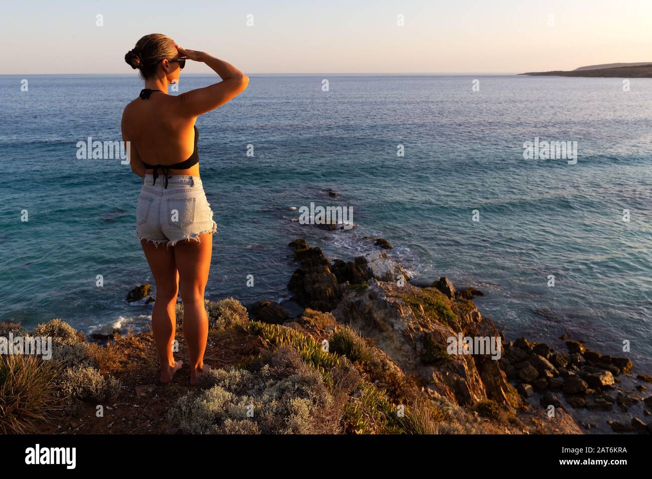 Junge Frau mit wunderschönem Blick auf Meer und Wüstenküste bei Sonnenuntergang in South Australia Stockfoto