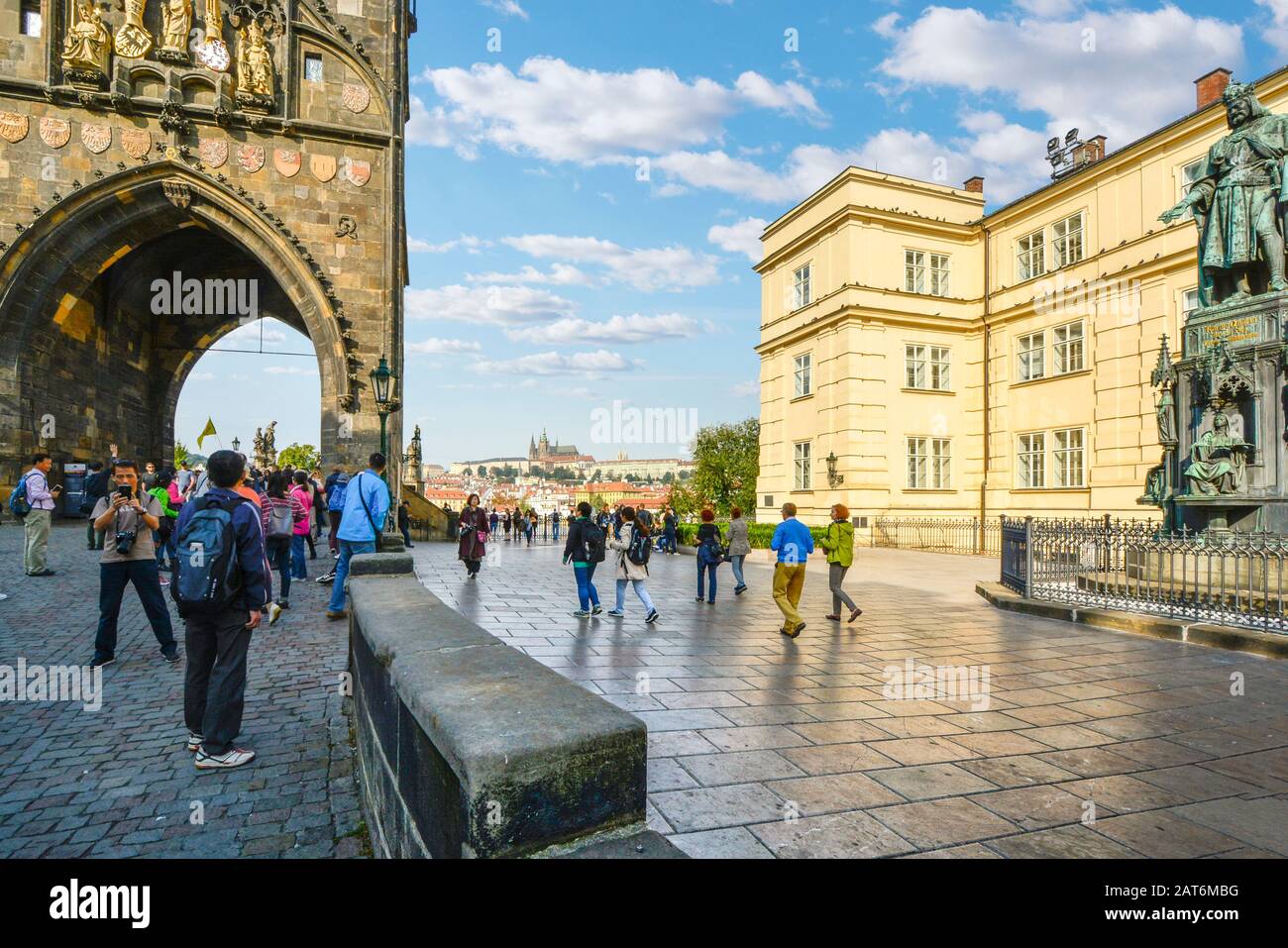 Touristen passieren die Statue von Karl IV. Und das Brückenmuseum durch den Altstadtturm mit dem Veitsdom in Prag, Tschechien. Stockfoto