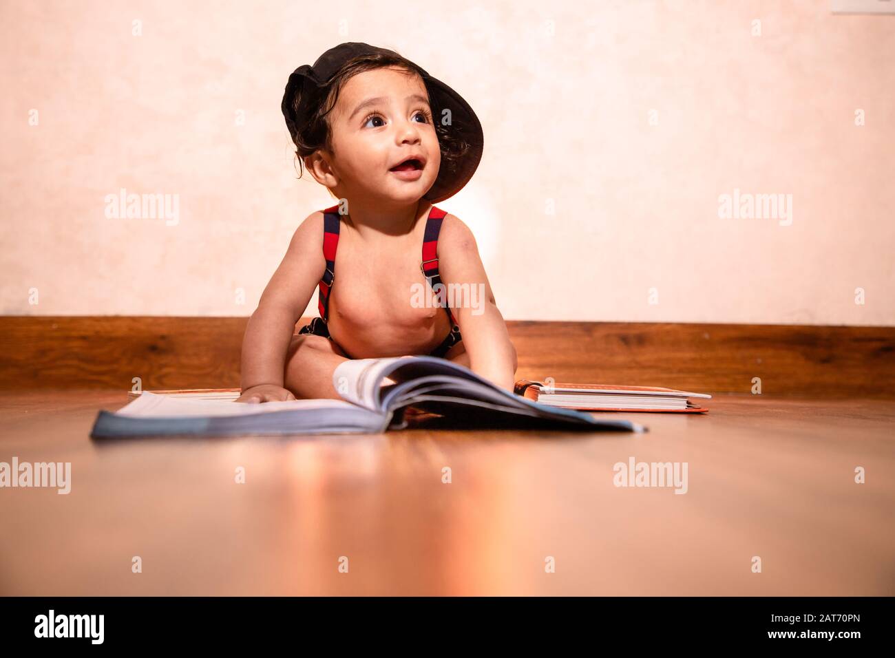 Kleinkind sechs Monate alten Baby Junge mit Buch suchen nach oben mit Lächeln. Baby Foto schießen niedrigen Engel Schuss Stockfoto