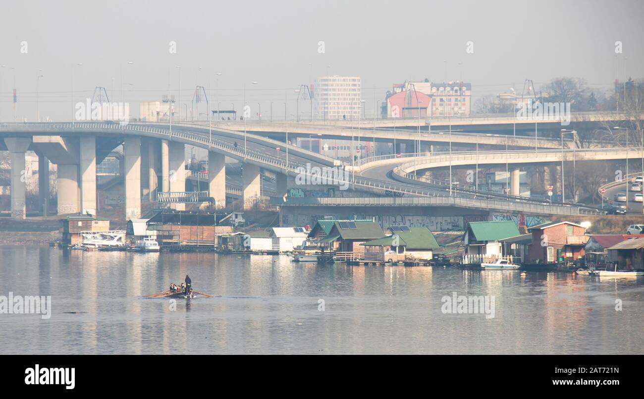 Belgrad, Serbien - 26. Januar 2020: Detail der Ada Brücke Zufahrtsstraßen über dem Fluss Sava mit Menschen Kajak fahren und Häuser auf Wasser Stockfoto