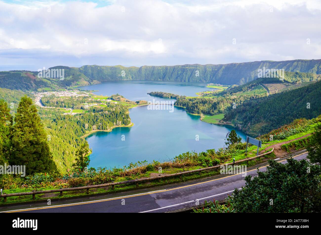 Wundervolle Aussicht auf die Seen Sete Cidades, fotografiert vom Aussichtspunkt Vista do Rei auf der Insel San Miguel, den Azoren, Portugal. Blauer Vulkansee umgeben von grünem Wald. Straße im Vordergrund. Stockfoto
