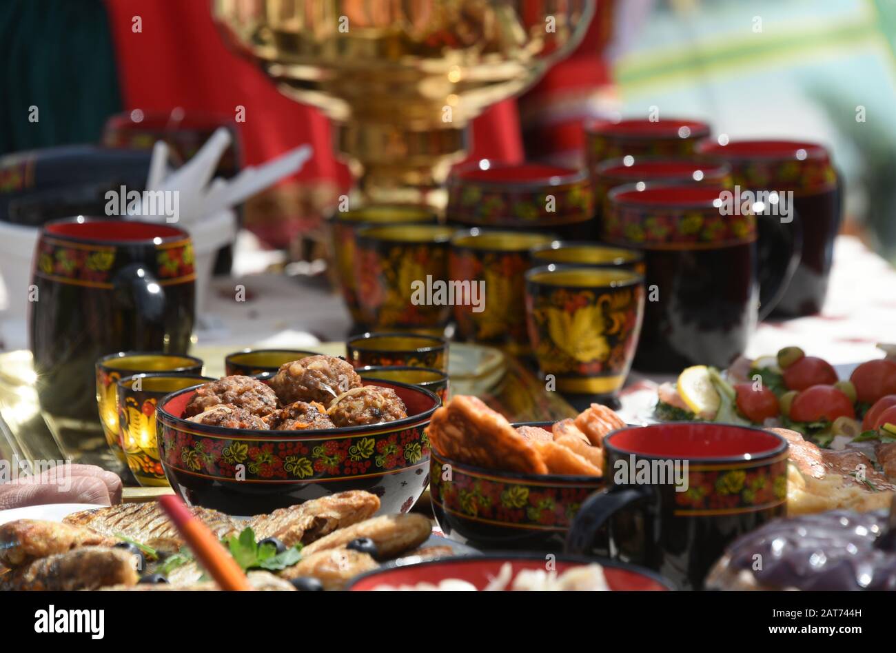 Satz Teetassen mit traditioneller russischer Zierde auf dem Tisch mit Samovar- und Fischgerichten Stockfoto