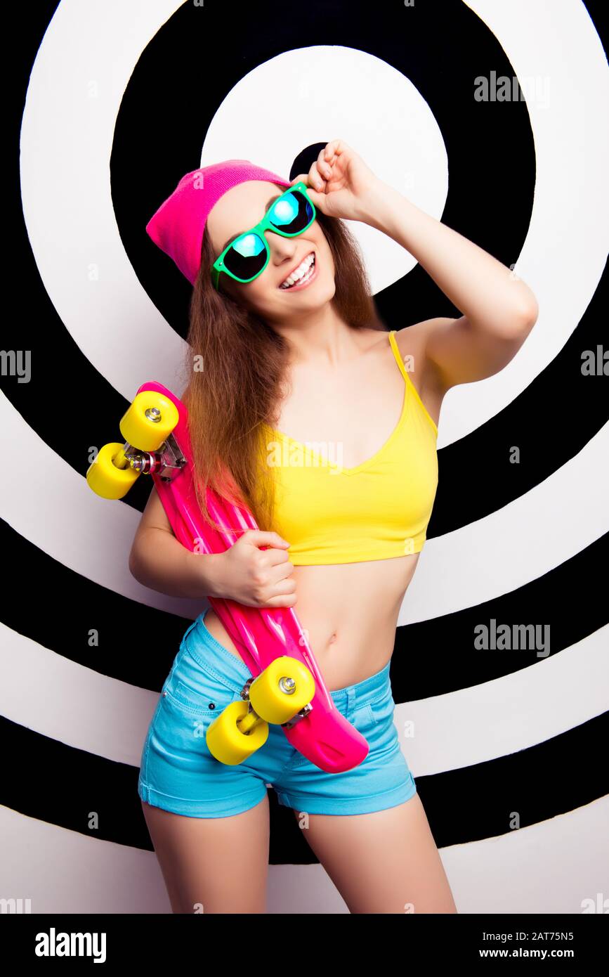 Glückliches Mädchen in Brillen, die Skate halten und ihren schlanken Bauch zeigen Stockfoto