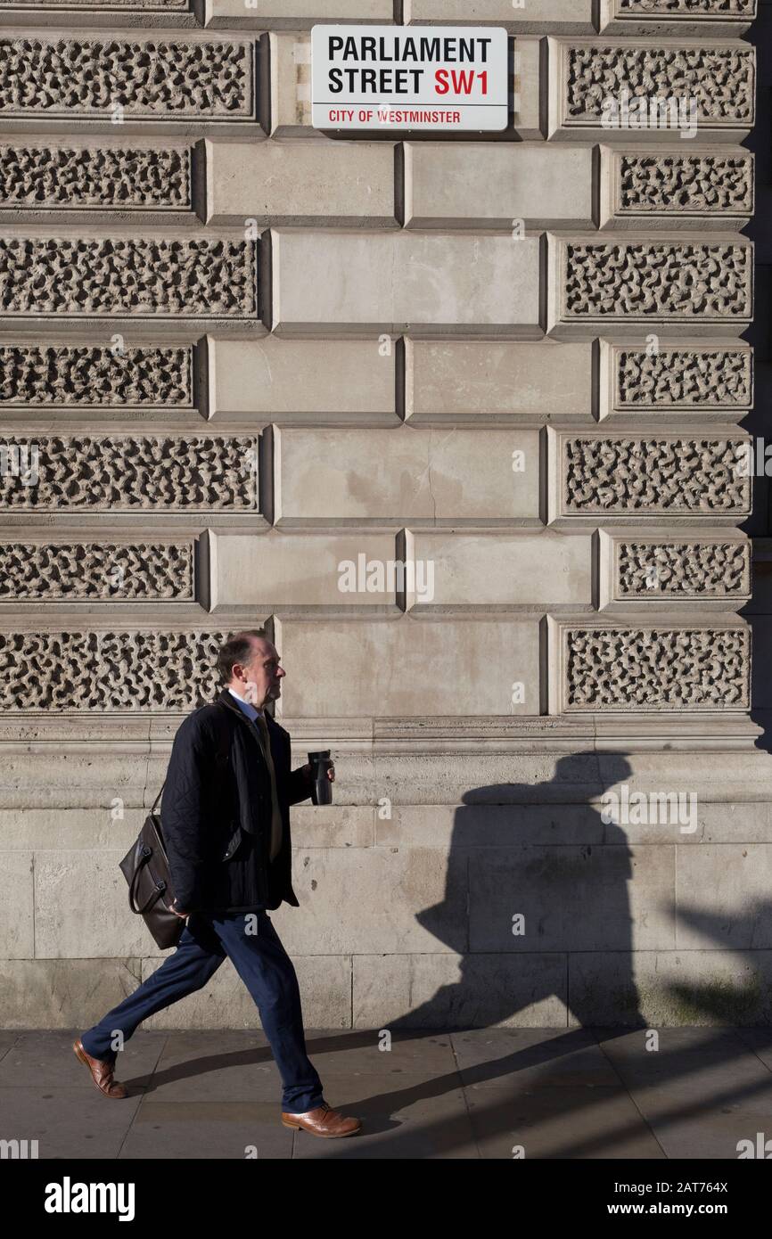 Ein Mann, der in Richtung Whitehall läuft, trägt am 29. Januar 2020 in London, England, eine Getränkekasse unter der Beschilderung für Parliament Street SW1, Westminster. Stockfoto