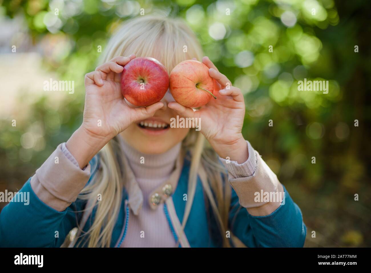 Portrait des Mädchens, das roten organischen apfel im Freien isst. Erntekonzept. Kind pflückt im Herbst Äpfel auf dem Bauernhof. Kinder und Ökologie. Gesunde Ernährung Ga Stockfoto