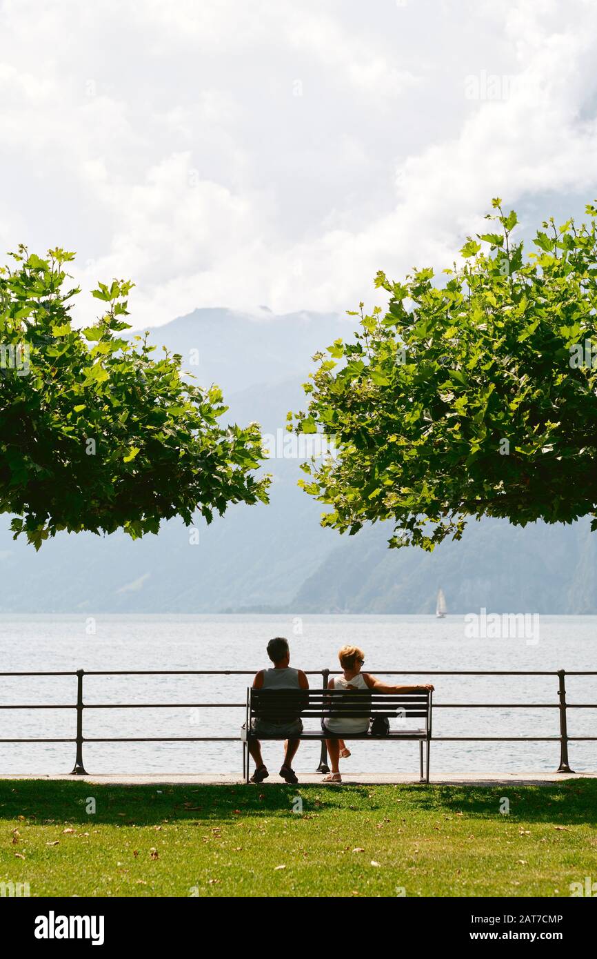 Ein pensionierter Paare, der sich auf einer Parkbank mit Blick über den Vierwaldstättersee in Brunnen, Schwyz, Schweiz, entspannen kann Stockfoto