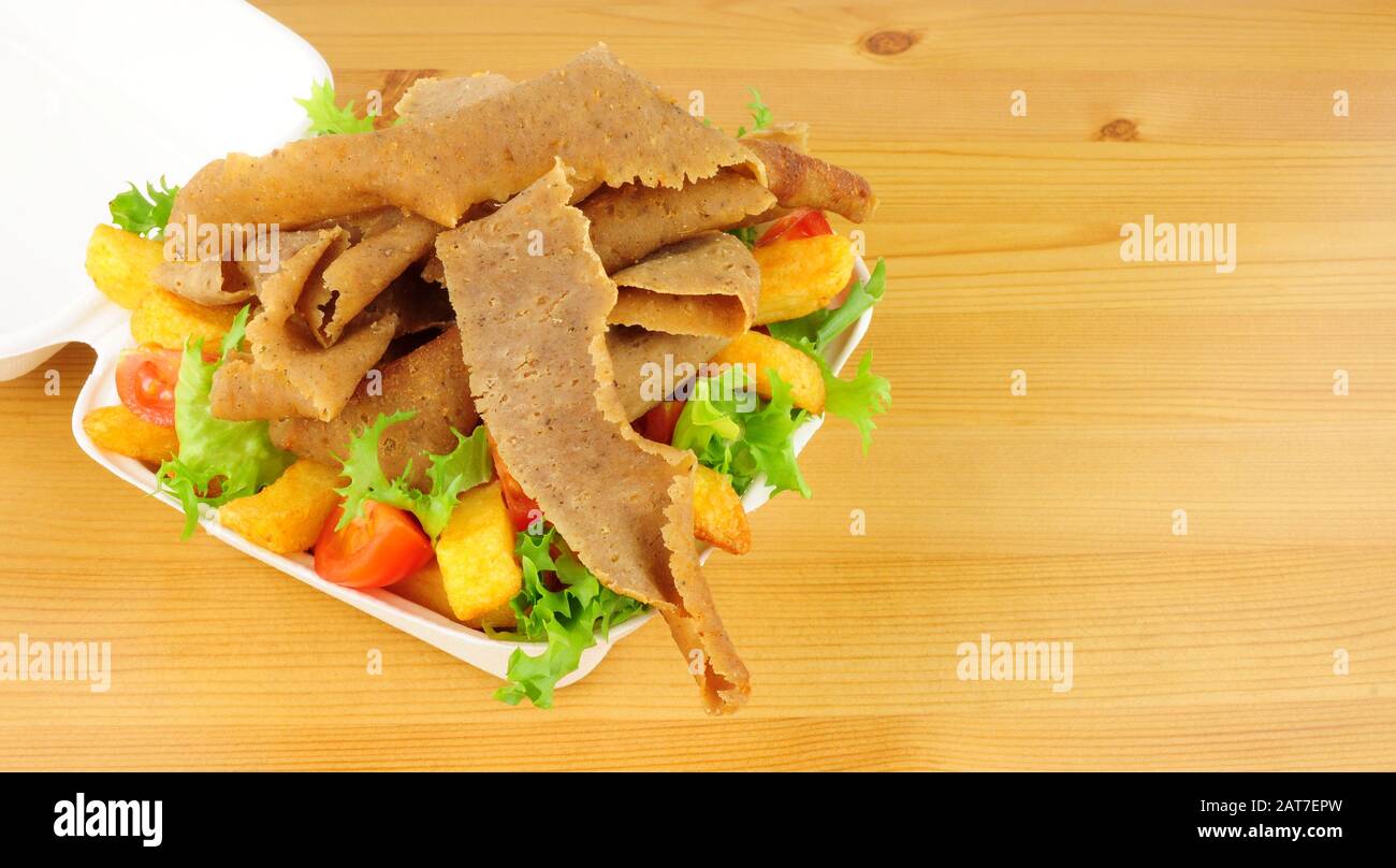 Nehmen Sie Kebabfleisch und Pommes mit Salat in einer offenen Fast-Food-Box weg Stockfoto