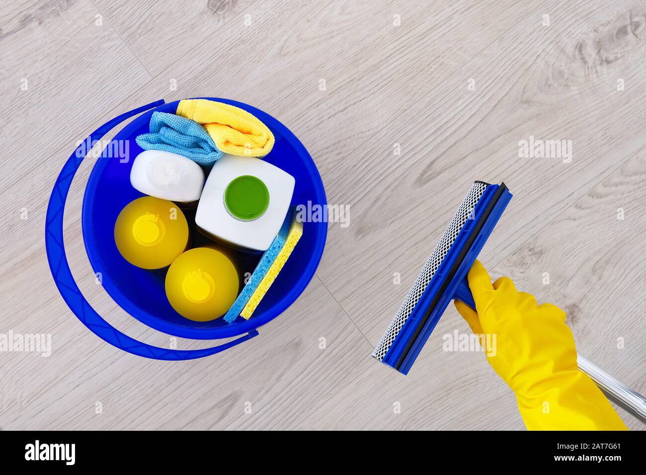 Waschmittel in Kunststoffflaschen, Schwämme in blauem Haushaltsbecher. Wischen Sie die Fenster in der Hand in gelbem Gummihandschuh. Servicekonzept. Kopierbereich. Stockfoto Waschmittel in Kunststoffflaschen, Schwämme in blauem Haushaltsbecher. Wischen Sie die Fenster in der Hand in gelbem Gummihandschuh. Servicekonzept. Kopierbereich. Stockfoto