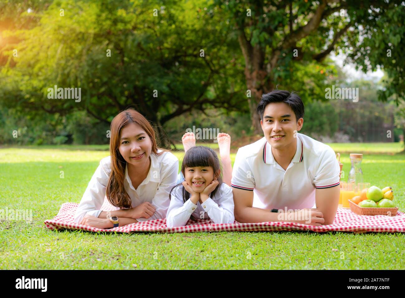 Asiatische Teenager Familie fröhlicher Urlaub Picknick-Moment im Park mit Vater, Mutter und Tochter liegen auf Matte und lächeln zu fröhlichen Urlaubszeiten zusammen Stockfoto