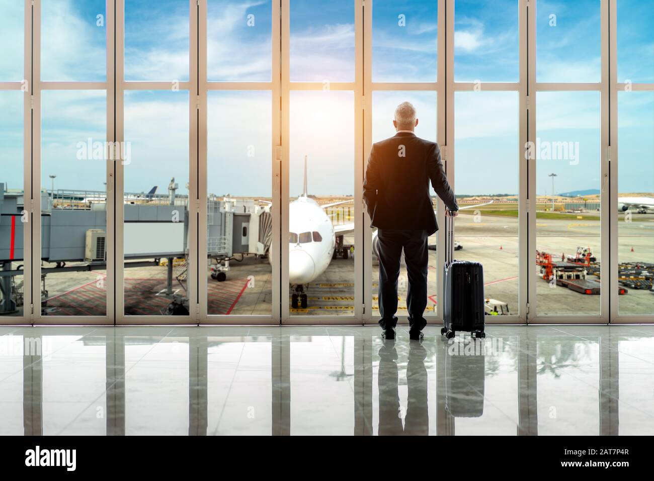 Geschäftsmann steht zusammen mit Gepäck in der Nähe des Fensters am Abflugplatz am Terminal des internationalen Flughafens. Businessstravel Konzept. Stockfoto