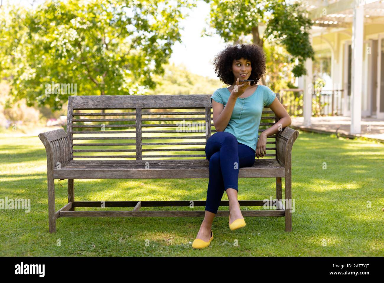 Junge Frau, die auf einer Bank im Garten sitzt Stockfoto