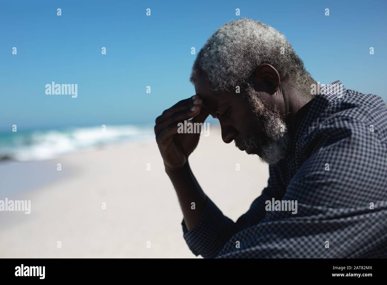 Alter Mann liest Buch am Strand Stockfoto
