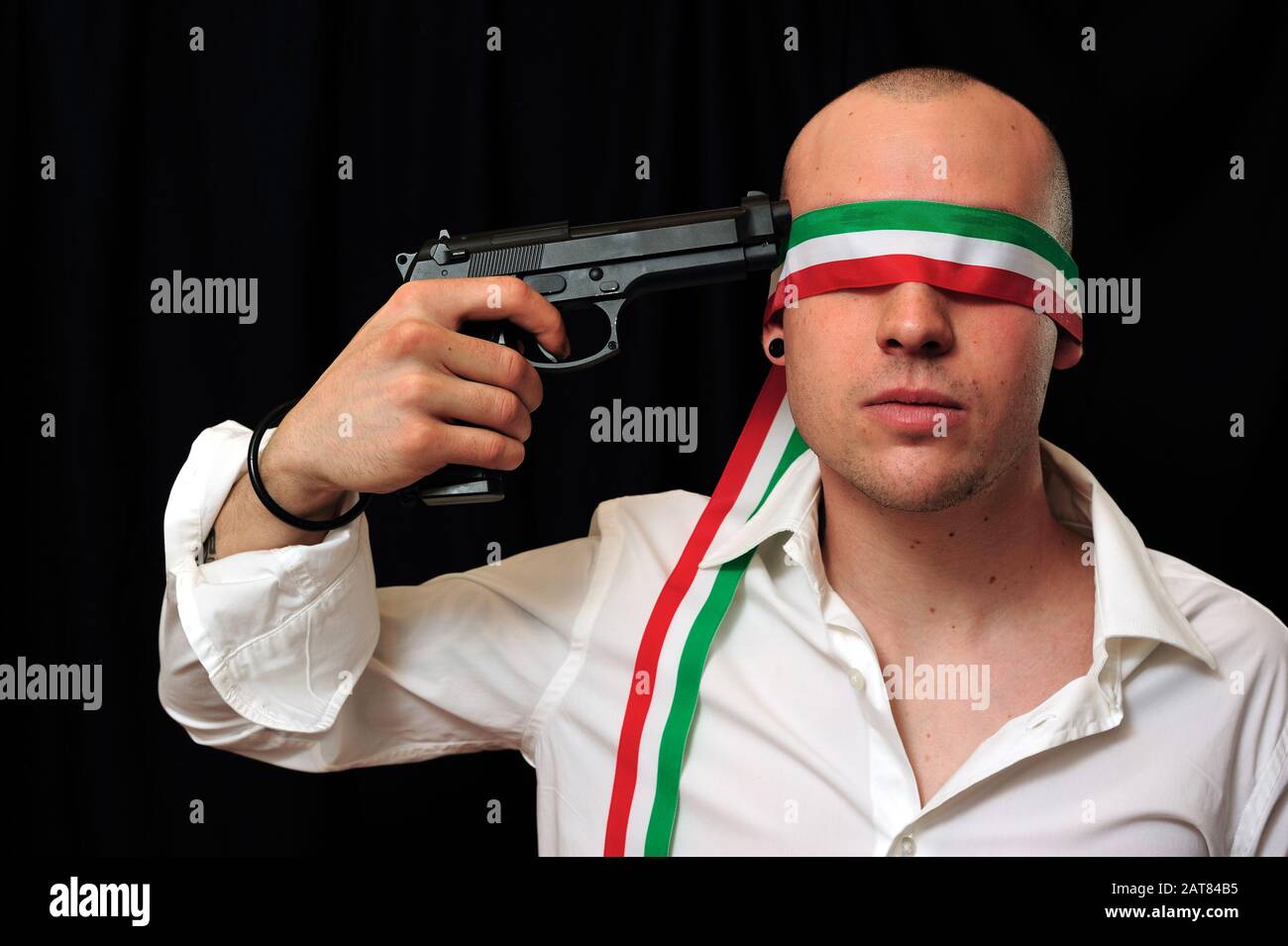 Junger Mann mit verbundenen Augen in weißem Hemd mit Pistole an den Kopf Stockfoto