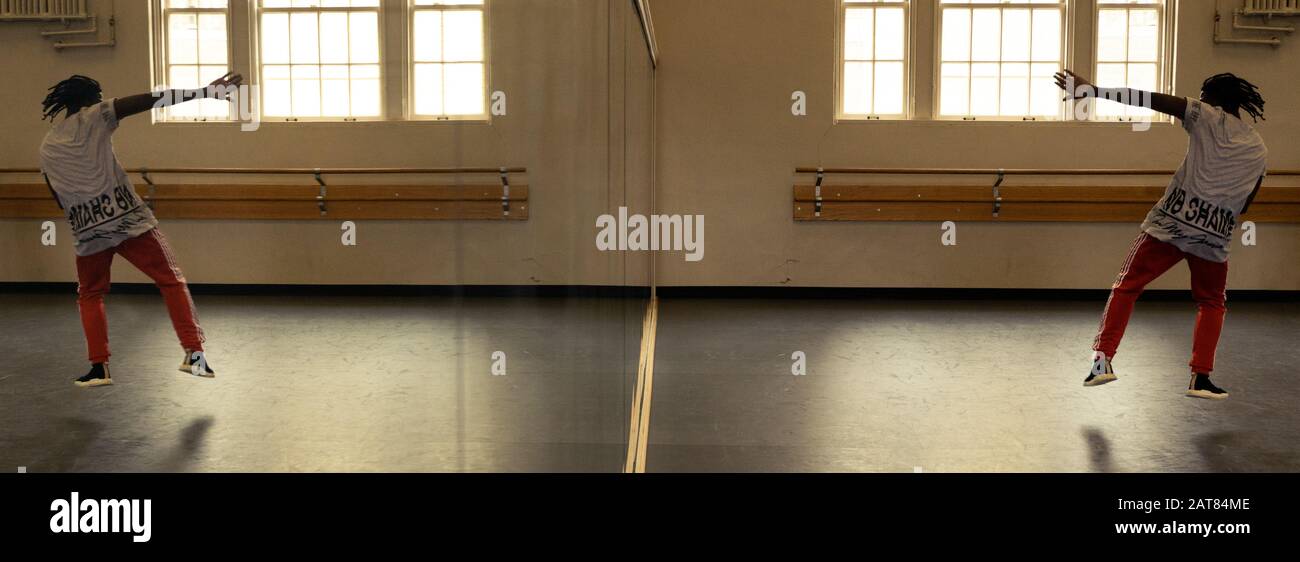 Tänzerin im Dance Studio Mit einem "Full Length Mirror and Reflection" mit einem "Black African American Man Jumping". Das Bild spiegelt die Tanzbewegung wider. Stockfoto