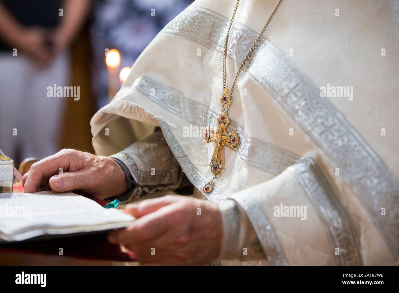 Orthodoxe Religion. Hände des Priesters vor dem Hintergrund des Kreuzes und der Kerzen. Stockfoto