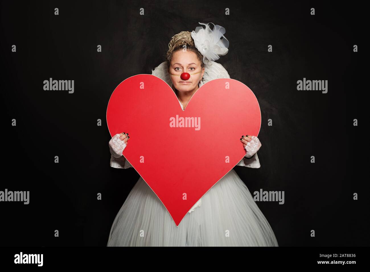 Frau Schauspielerin hält rotes leeres Herzbanner auf schwarzem Hintergrund Stockfoto