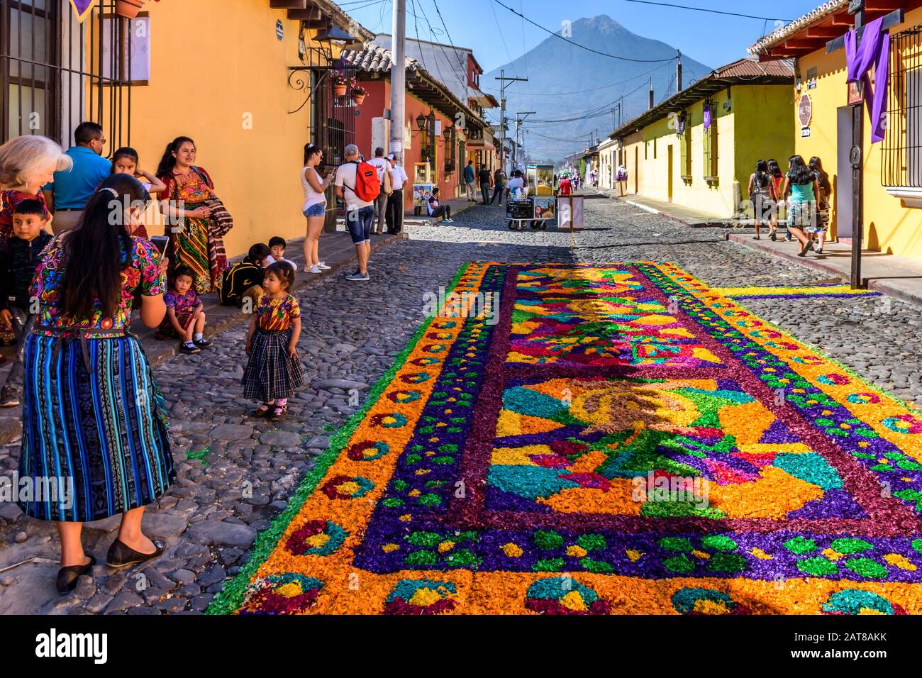 Antigua, Guatemala - 14. April 2019: Maya Family & Palm Sunday Prozession Teppich mit Agua Vulkan hinter in der UNESCO-Welterbestätte. Stockfoto