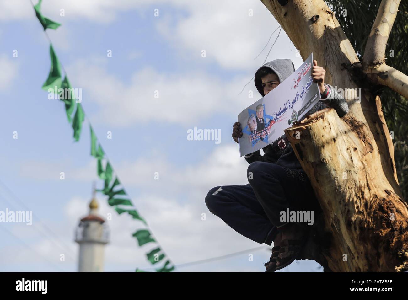 31. Januar 2020, Gaza-Stadt, Gaza-Streifen, Palästina: Ein palästinensischer Junge, der einen Baum klettert, hält ein Banner mit der Lektüre "'Deal of Century is a Dolger in the Taille of Muslims'" während eines Protestes gegen den Nahost-Friedensplan des US-Präsidenten Donald Trump im nördlichen Gazastreifen am 31. Januar 2020. (Bild: © Mahmoud Issa/Quds Net News über ZUMA Wire) Stockfoto