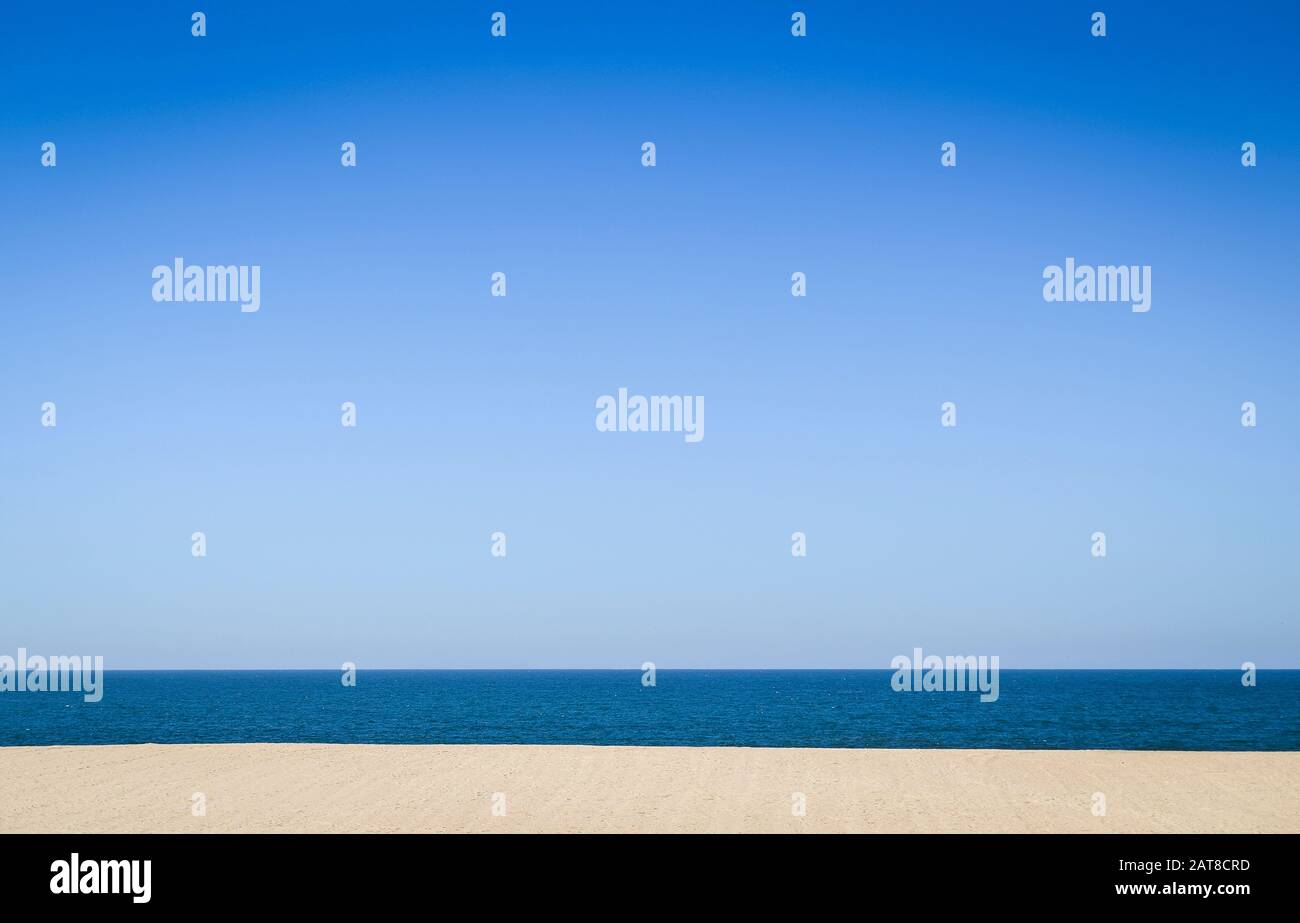 Ein leerer sandiger Strand und Meer, Blick auf das Meer unter einem klaren blauen Himmel. Stockfoto