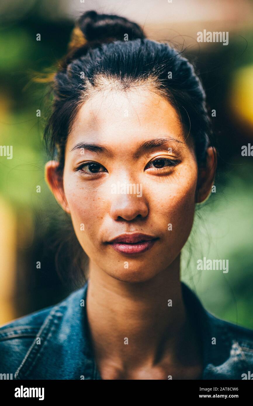 Porträt einer jungen Frau mit schwarzen Haaren, die in einem Knoten gefesselt sind, mit Blick auf die Kamera. Stockfoto