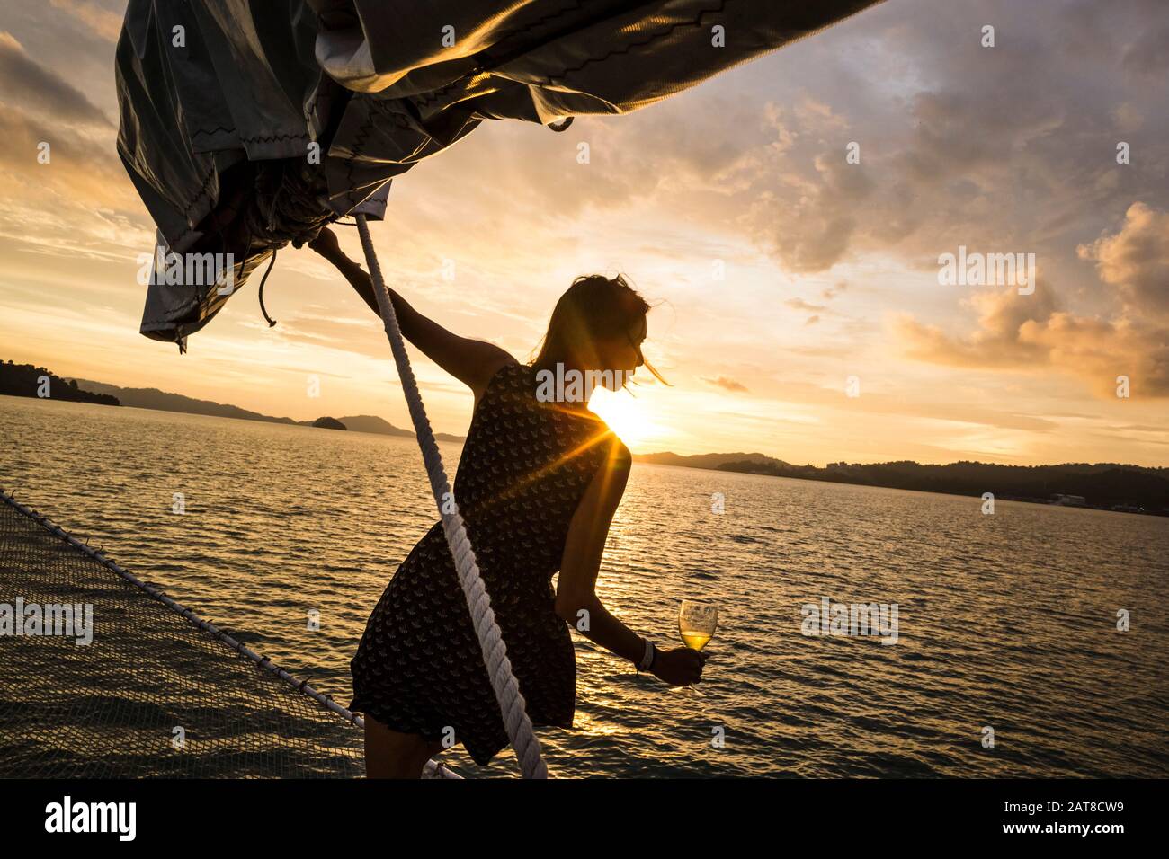 Frau, die Weinglas an Bord eines Bootes hält, Bootstour zum Abendessen bei Sonnenuntergang auf dem Indischen Ozean. Stockfoto