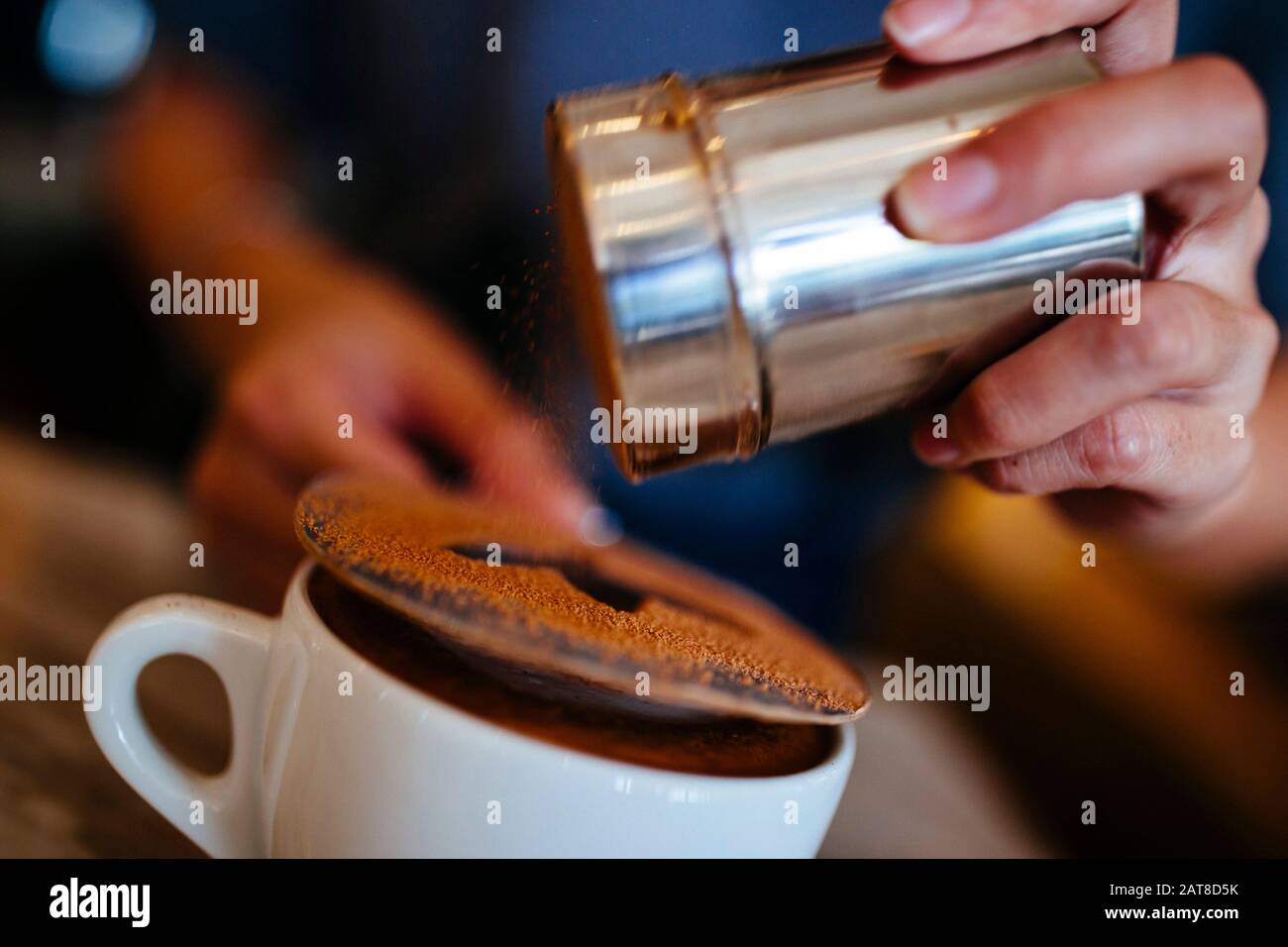 Nahaufnahme des Barista, der die letzten Schliff auf einen Mokka legt. Stockfoto