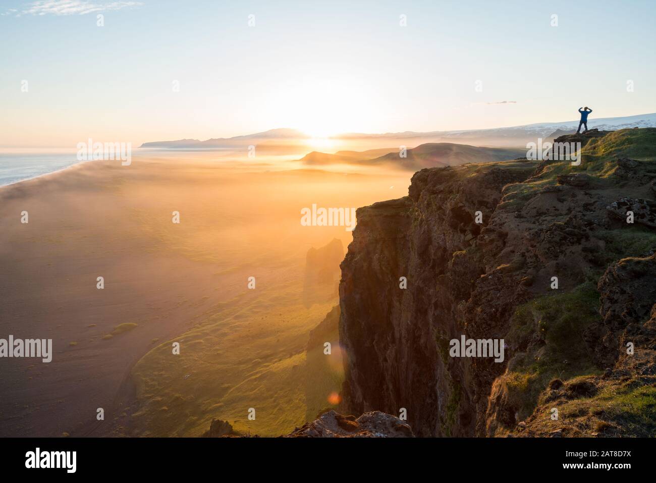 Mann, der den Blick auf den Sonnenuntergang von der Dyrholaey-Halbinsel in der Nähe von Vik, Südisland (Sudurland), Island, Polarregionen betrachtet Stockfoto