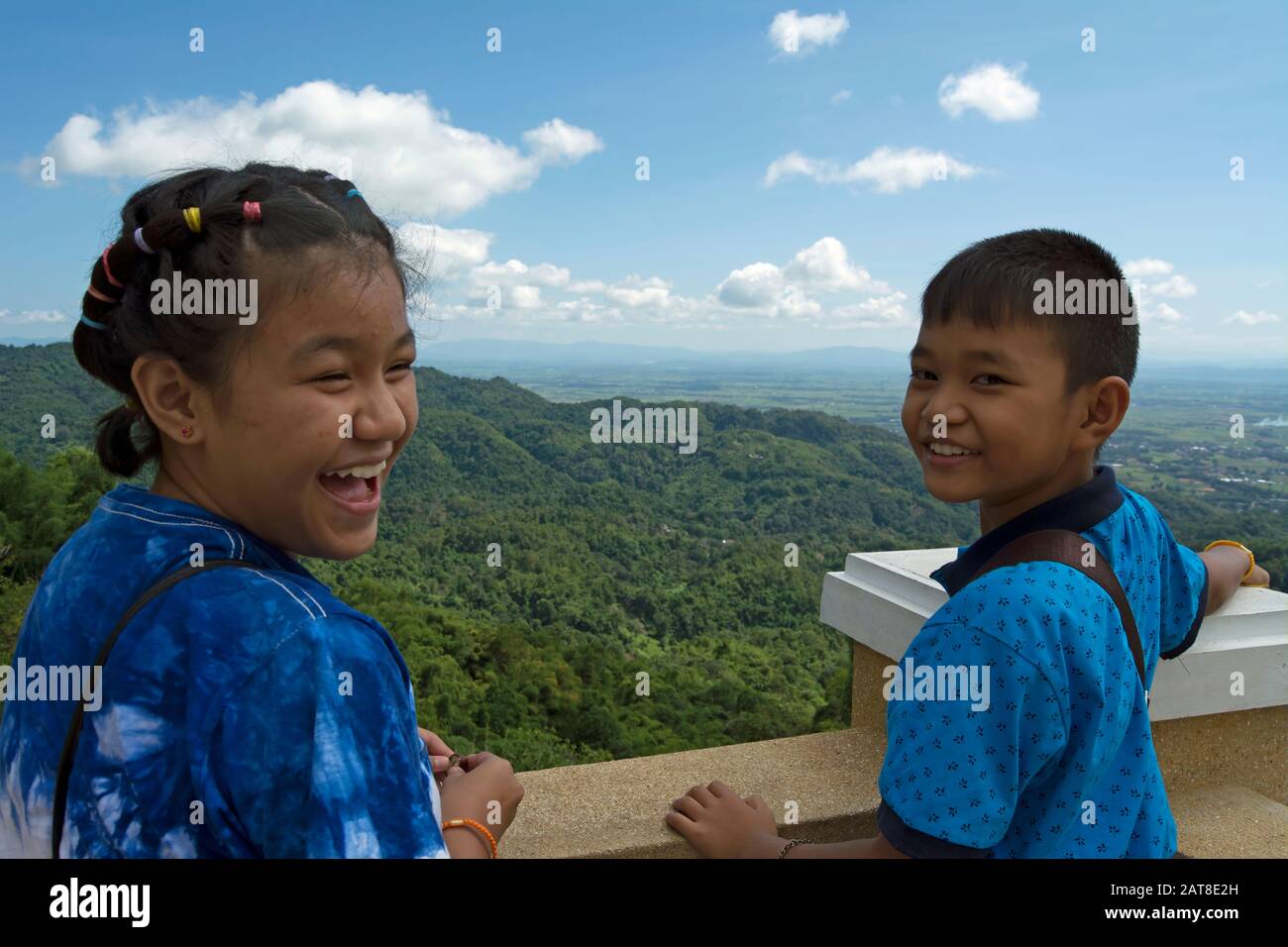 Auf einer Aussichtsplattform in den Hügeln nordthailands drehen sich zwei kleine thailändische Kinder den Kopf und lächeln Stockfoto