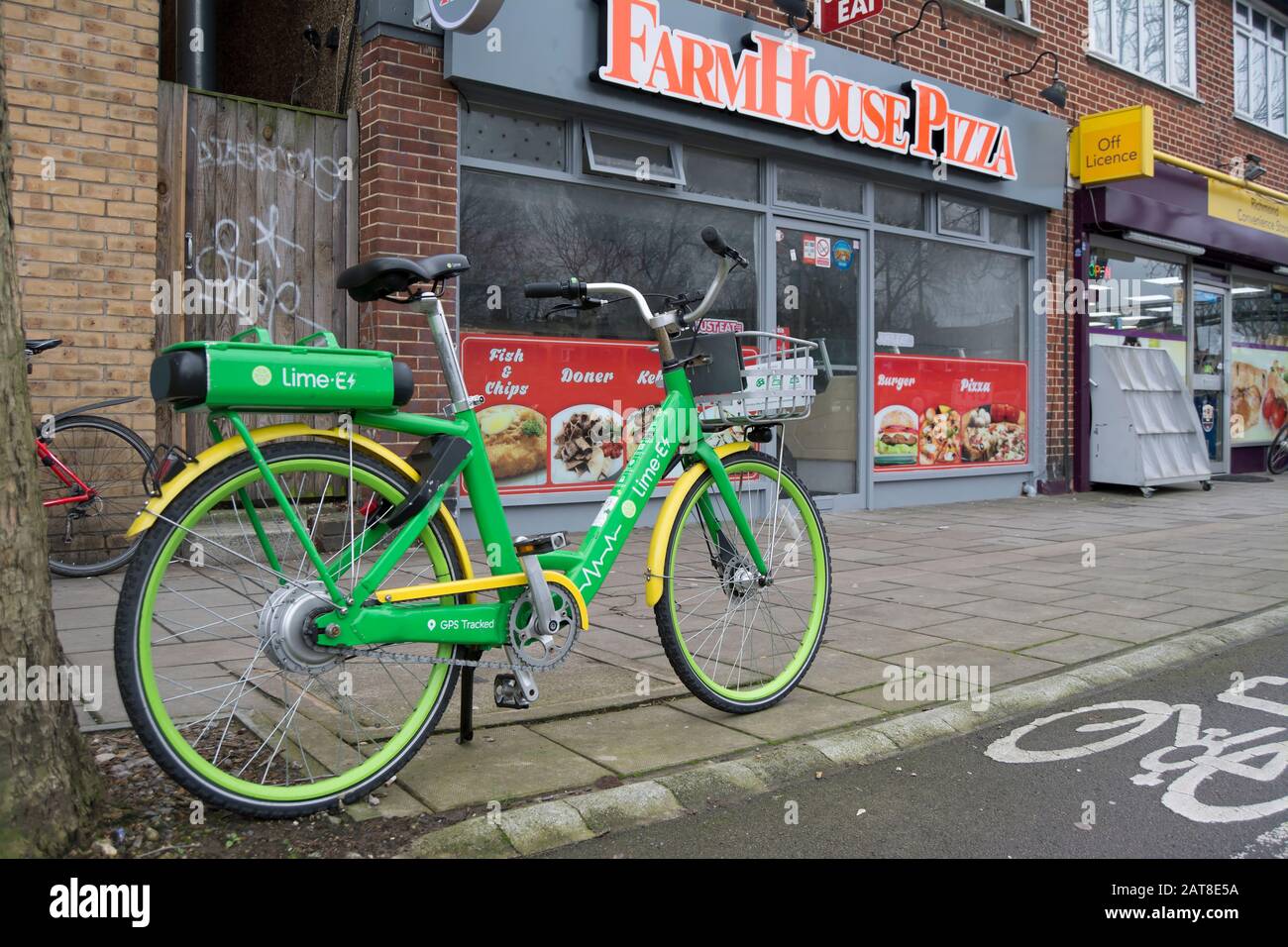 Ein andockeloses elektrisches Fahrrad, das neben einer Radfahrbahn vor einem Bauernhaus geparkt wurde, Pizza Takeaway in Ostsheen, london, england Stockfoto