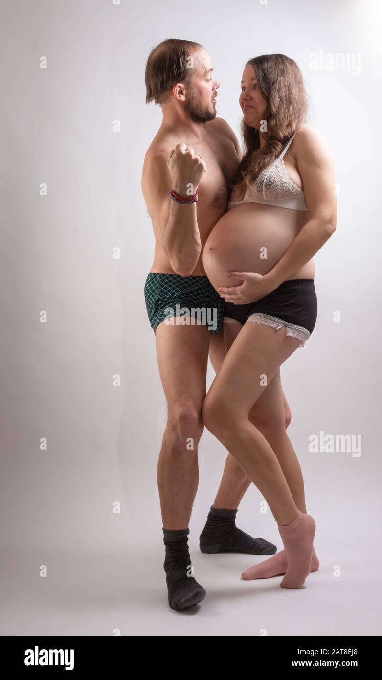 Schöne schwangere Frau und ihr gutaussehender Mann küssen, während sie Zeit zusammen im Bett verbringen. Stockfoto