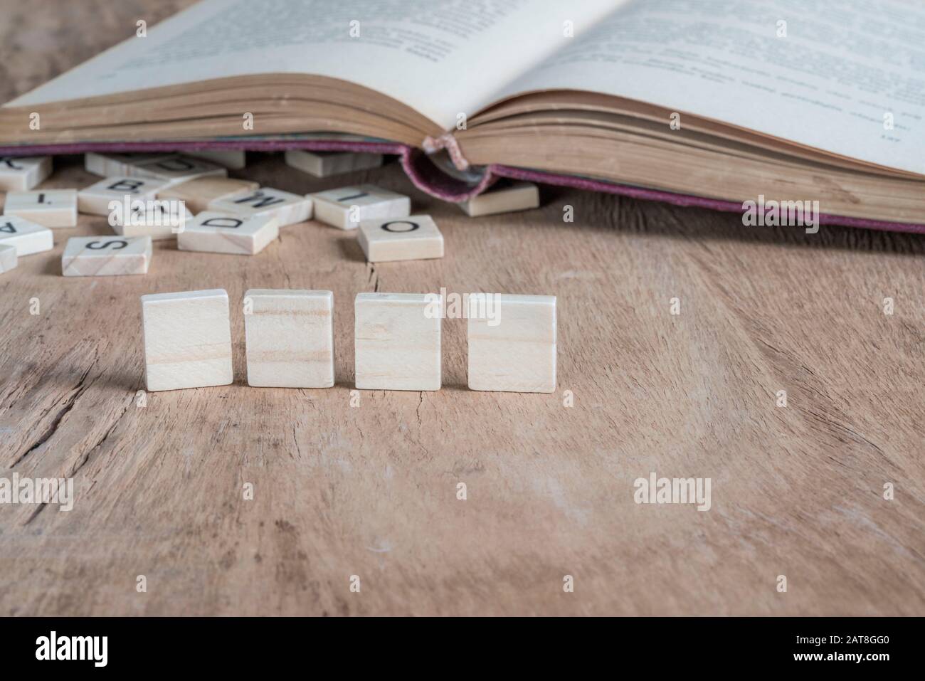 Vier leere Würfel auf einem Holztisch gegen altes Buch Stockfoto