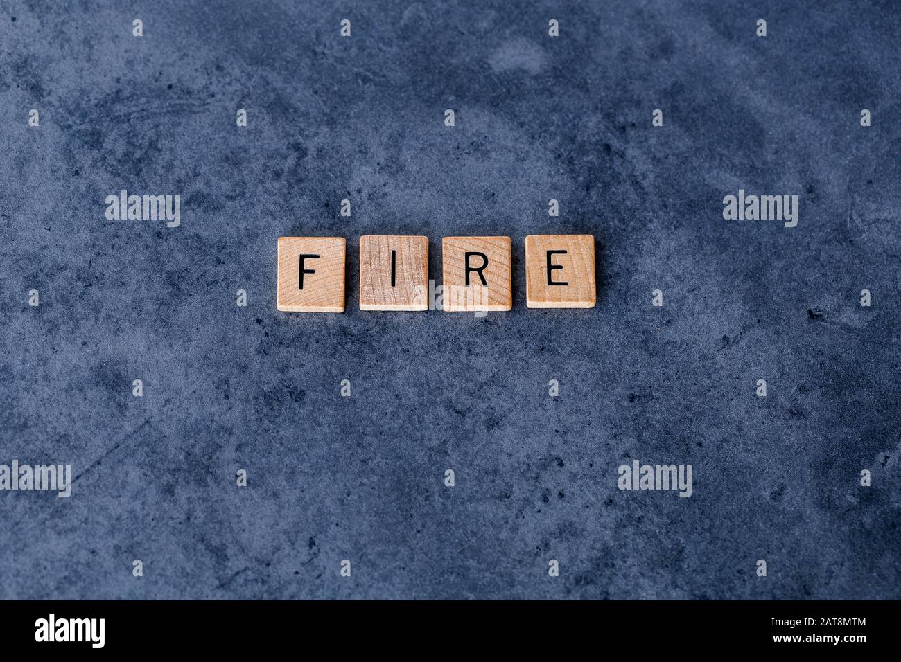 "Feuer" buchstabierte in Holzfliesen auf dunklem, rauem Hintergrund Stockfoto